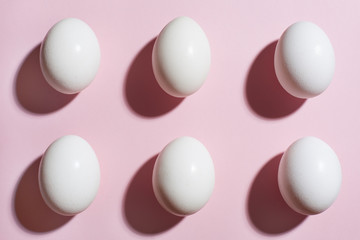 Eggs background. Six white eggs on a pink paper backdrop. Top view, flat lay.