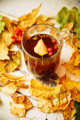 Autumn leaves and hot steaming cup of coffee. Wooden table on sun light background. Fall time concept.