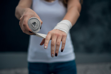 girl dressed in white t-shirt preparing for the competition waving her hands with a bandage