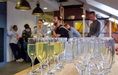 Glasses with champagne in the foreground, blurred people on the background. Concept of a party, event, catering