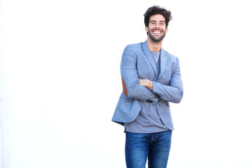 Handsome man standing with arms crossed smiling by white wall