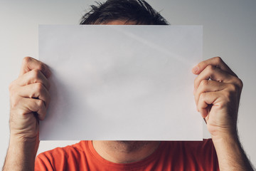 Man hiding behind blank white paper