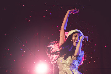 Happy woman dancing under confetti at a party