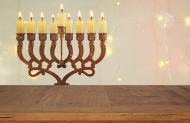 Empty wooden table in front of jewish holiday Hanukkah background with menorah (traditional candelabra)