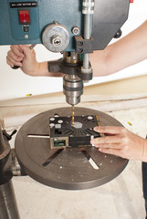 Technician destroying data on a hard drive by drilling through the platters with a Drill Press or a electric hand drill