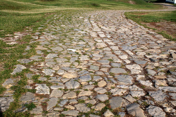 Ancient winding road paved with cobblestone .