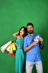 Couple in love holds shopping bags on green background.