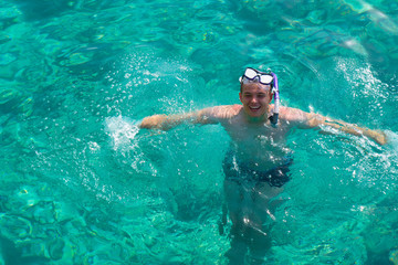 Man with snorkeling mask for diving swimming in the Indian ocean at Maldivian island. Man is snorkeling in the tropical sea. Happy man Enjoying snorkelling with clear blue water in the Maldives ocean.