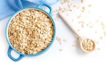 Oat flakes plate with milk, orange, eggs on a wooden white table. Top view of healthy oat flakes breakfast. Copy space. blue napkin Breakfast in bed plate, breakfast table buffet. Healthy ingredients.