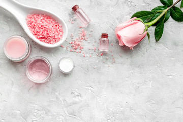 Natural organic cosmetics with rose oil. Cream, lotion, spa salt on grey background top view copyspace