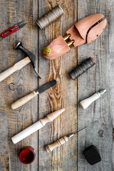 Clobber tools pattern. Wooden last, hammer, awl, knife, thread on wooden background top view