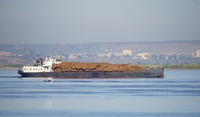 Fototapeta na wymiar Transportation of timber along the Volga River by boat