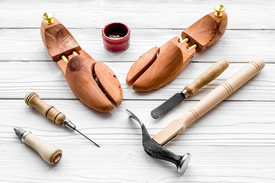 Tools for repair shoes. Wooden last, hammer, awl, knife, thread on white wooden background