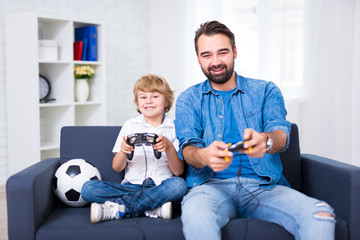 father and son playing video games at home