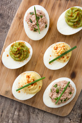 Variety of stuffed eggs with avocado and tuna  on wooden table.Top view