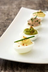 Variety of stuffed eggs with avocado and tuna  on wooden table