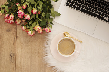 Feminine workplace concept. Freelance workspace with laptop, flowers roses. Blogger working.