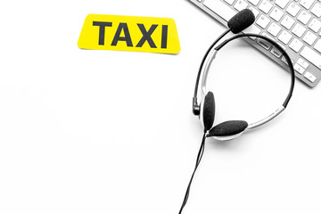 Taxi service online. Taxi label, keyboard, headphones on white background top view copyspace