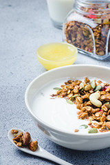 Chewy honey coconut granola yogurt bowl on dark concrete background. Selective focus, copy space.