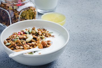 Honey nuts granola yogurt breakfast bowl on dark concrete background. Selective focus, copy space.