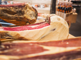 Jamon serrano. Traditional Spanish ham in the market close up. Pork leg ham on table. Meat in restaurant interior. Whole jamon on stand. Selective focus. Gourmet ham. Shallow DOF. Copy space.