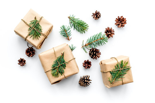 Gifts for new year wrapped in craft paper near spruce branches and cones on white background top view