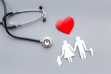 Take out health insurance for family. Stethoscope, paper heart and silhouette of family on grey background top view