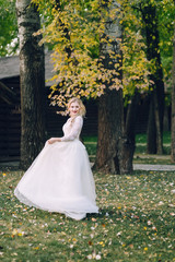 Happy bride is posing in fluttering dress on nature. Artwork