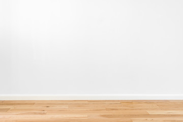 White painted stucco wall and natural wooden ash-tree 3-band parquet board hardwood floor. Flooring in scandinavian style of empty interior with wide white baseboards. Light brown, biscuit color