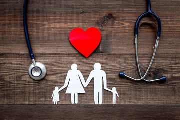 Take out health insurance for family. Stethoscope, paper heart and silhouette of family on wooden background top view - obrazy, fototapety, plakaty