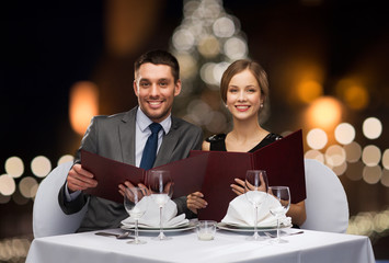 smiling couple with menus at christmas restaurant