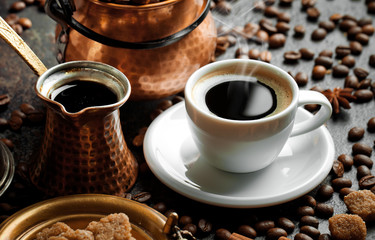 Black coffee in a cup on the table in a composition with coffee accessories on an old background
