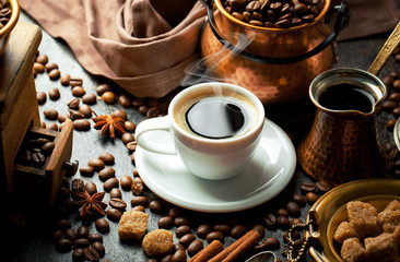 Black coffee in a cup on the table in a composition with coffee accessories on an old background