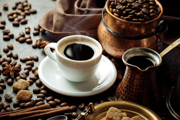 Black coffee in a cup on the table in a composition with coffee accessories on an old background