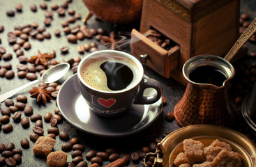 Black coffee in a cup on the table in a composition with coffee accessories on an old background