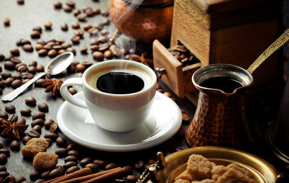 Black coffee in a cup on the table in a composition with coffee accessories on an old background