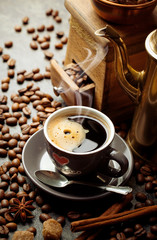 Black coffee in a cup on the table in a composition with coffee accessories on an old background