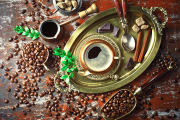 Black coffee in a cup on the table in a composition with coffee accessories on an old background