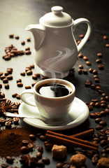 Black coffee in a cup on the table in a composition with coffee accessories on an old background