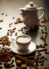 Black coffee in a cup on the table in a composition with coffee accessories on an old background