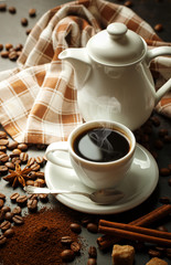 Black coffee in a cup on the table in a composition with coffee accessories on an old background