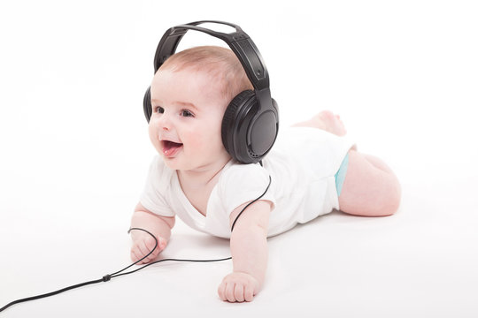 Charming Baby On A White Background With Headphones Listening To Music