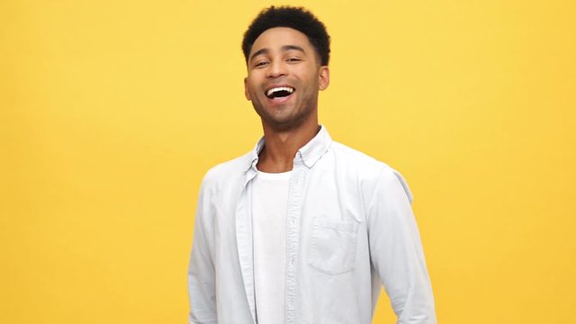 Happy Young african man in shirt walking and meets someone over yellow background