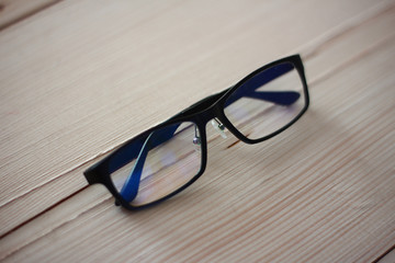  Black eyeglasses on wood plate.