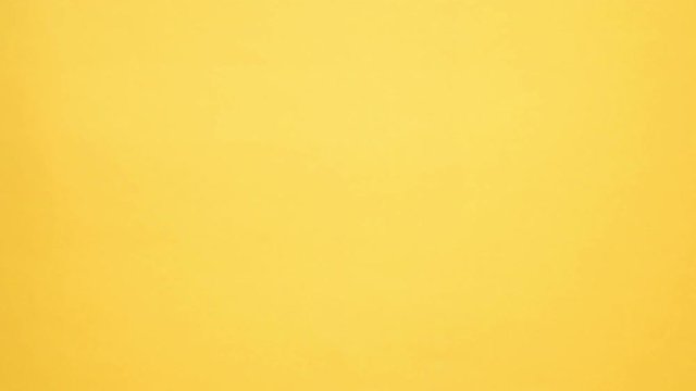 Young african man in shirt meets someone and walking away while covering his face over yellow background

