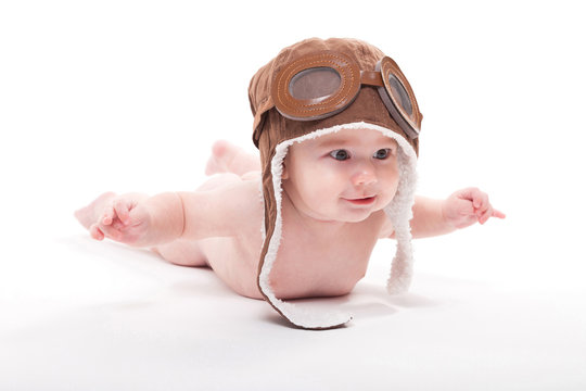 Naked cute smiling baby in the cap of the pilot is flying on a white background