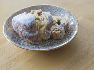 close up sliced traditional german marzipan stollen christmas candy on plate on wooden background