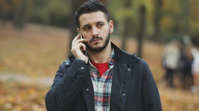 handsome bearded young man talking phone mobile confident serious calm face app business administration negotiation discussion agreement autumn beautiful park blur background argument businessman male