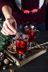girl puts a cinnamon stick in hot mulled wine