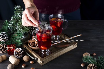 girl puts a cinnamon stick in hot mulled wine